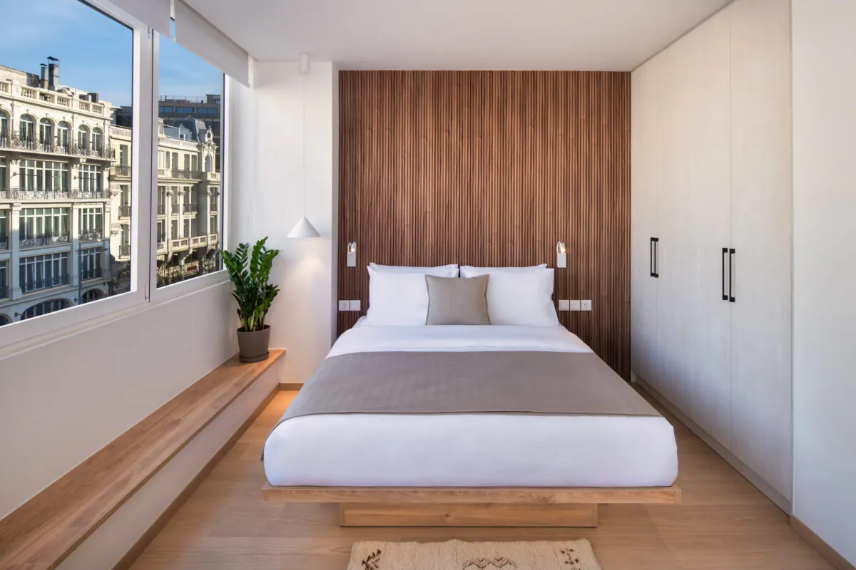 Schlafzimmer mit Holzwand und Blick auf historische Fassaden