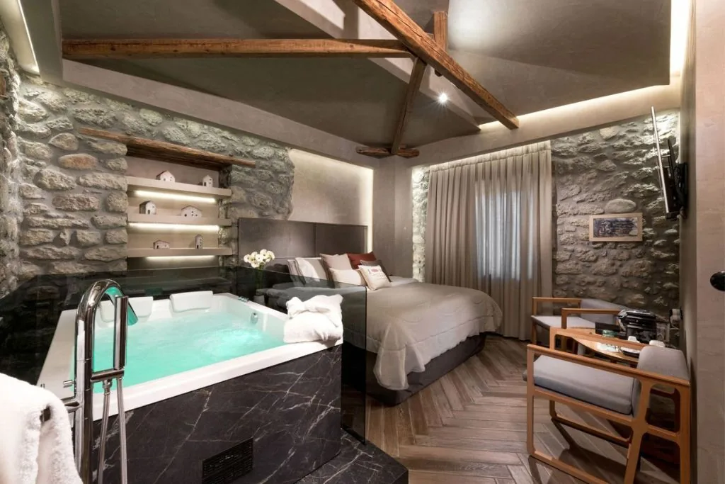 Jacuzzi Suite mit Steinwänden und Holzbalken